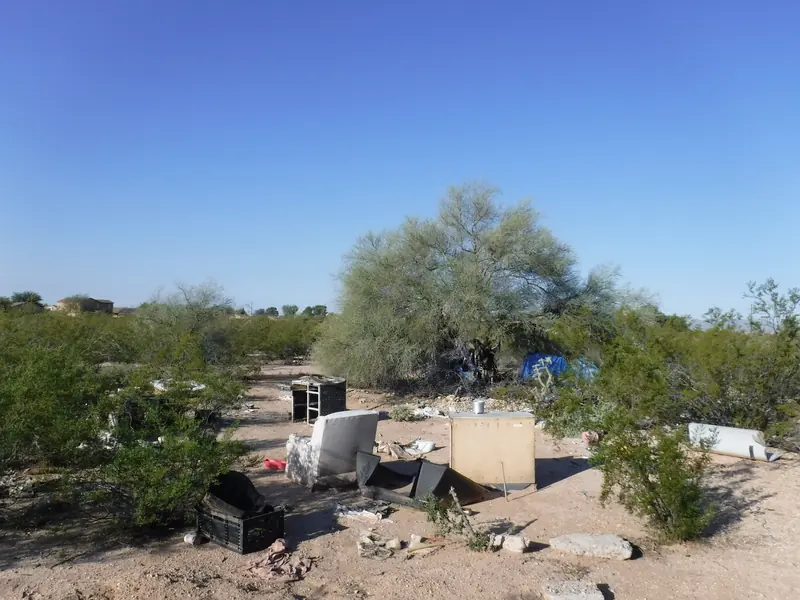 Homeless camp cleanup before: furniture, crates and trash left in the desert brush