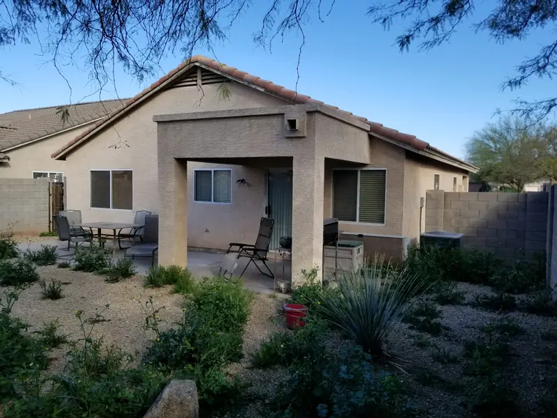 Backyard cleanup before: weeds and overgrowth around a patio