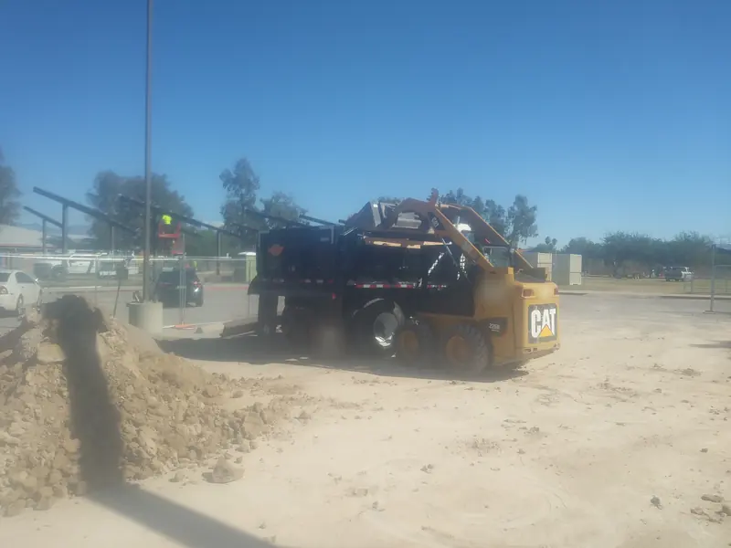 Construction cleanup: a skid steer loading dirt into a dump truck on a commercial site