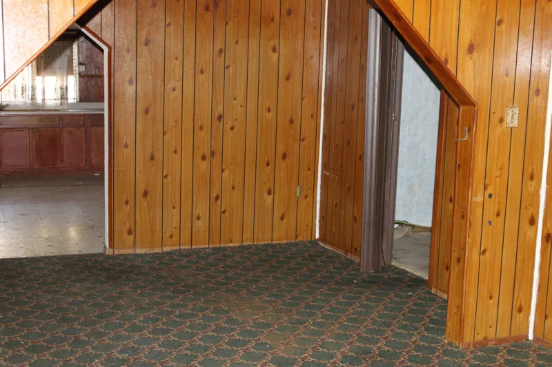 Foreclosure trash out, after: the paneled living room cleared, with the empty kitchen beyond
