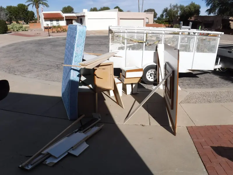 Junk removal before: a mattress, furniture and boards piled at the curb