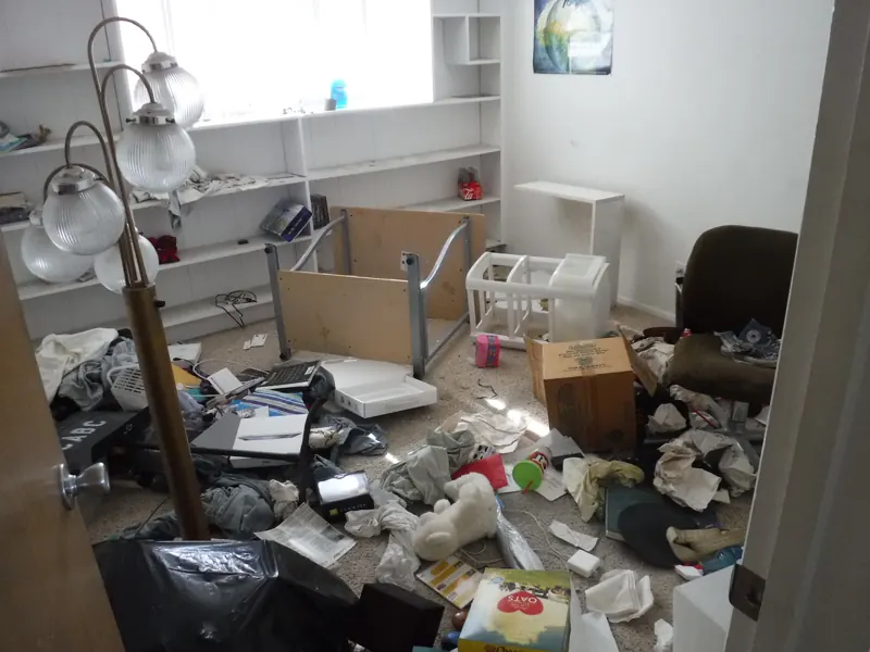 REO trash out, before: a bedroom left full of clothes, boxes, an overturned desk and trash