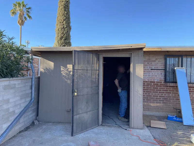 Shed removal in Tucson, before: a wood shed against a block wall