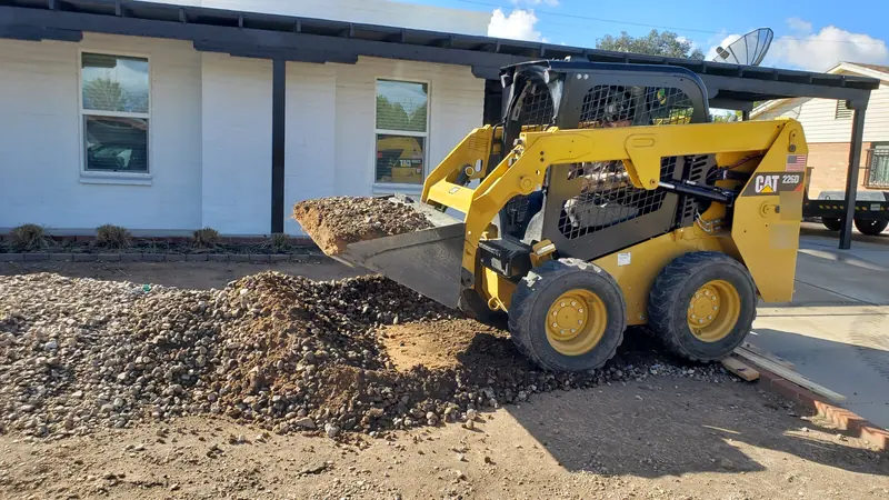 Gravel removal in Tucson: a skid steer scooping up rock and dirt scraped off the ground